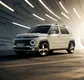 Hyundai Inster in Halbfrontansicht vor einer geschwungenen Betonwand